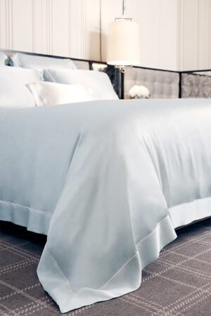 Detail view of MANITO Authentic Silk Duvet Cover in baby blue color showcasing the elegant border trim and natural drape.