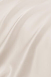 Smooth and lustrous texture of the ivory MANITO Authentic Silk Fitted Sheet fabric.
