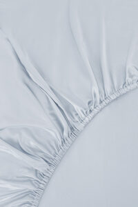 Close-up of elastic edge on the light blue version of MANITO Authentic Silk Fitted Sheet.