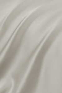 Soft folds and sheen of the taupe-colored MANITO Authentic Silk Fitted Sheet fabric.