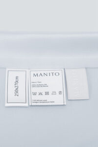 Product label on the MANITO Authentic Silk Flat Sheet showing size and care instructions.