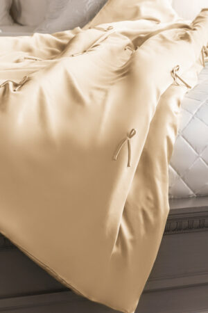 Champagne Silk Throw Blanket draped across the bed showing its smooth satin finish and ties.