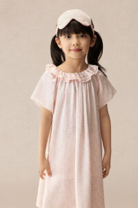 Girl wearing BONPOINT×MANITO Celestial Kid's Nightdress Gift Box in soft pink silk with matching eye mask and ruffled neckline.