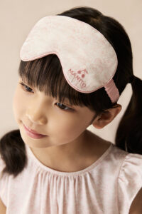 Close-up of pink floral silk eye mask from BONPOINT×MANITO Celestial Kid's Nightdress Gift Box worn by a child.