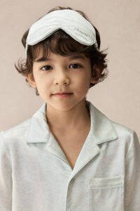 Child wearing BONPOINT×MANITO Clive Kid's Pajama Set Gift Box with matching embroidered silk eye mask.