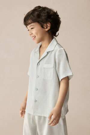 Side view of a smiling child in BONPOINT×MANITO Clive Kid's Pajama Set Gift Box.