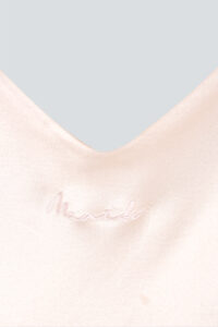 Close-up of the basal round-neck silk nightdress showing the embroidered brand name "MANITO".