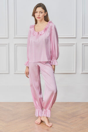 Woman wears Blooming Women's Pajama Set in pink, standing barefoot in a calm room for a soft, relaxed mood.