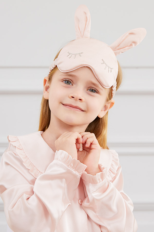 A child wears Bunny Child Eye Mask with rabbit ears and diamond eyelash detail, styled with silk pajamas.