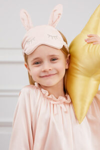 Smiling child poses in Bunny Child Eye Mask with soft silk fabric and rabbit ear shape.