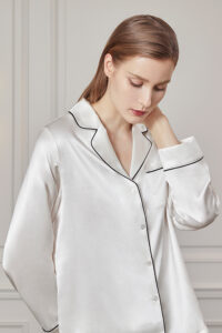 Woman in contemplative pose wearing an Authentic Women's Silk Pajama Set in white.