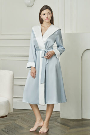 Woman wears Calla Women's Hooded Bathrobe in baby blue silk, exuding soft morning elegance and effortless comfort.
