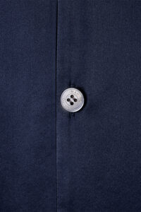 Button detail on MANITO Chemise Mashinen silk pajama shirt, showcasing branded button with clean stitched placket.
