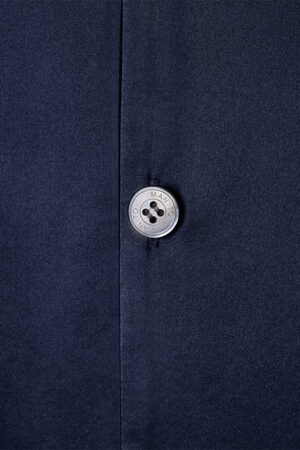 Button detail on MANITO Chemise Mashinen silk pajama shirt, showcasing branded button with clean stitched placket.