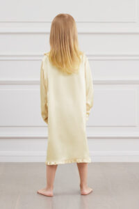 Back view of a girl wearing a yellow Cloud Silk Nightgown with a ruffled hem.