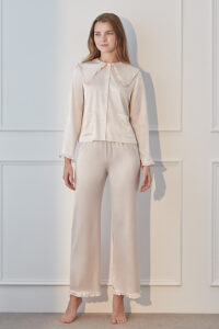 A woman wearing MANITO Cloud cute pink pajama set featuring a ruffled collar and buttons, paired with matching pants.