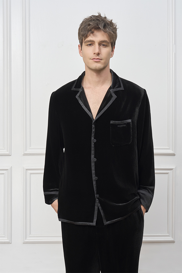 Man wears Combo Velvet Pajama Set in black, standing relaxed with hands in pockets and satin-trimmed collar showing.