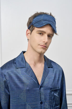 Model poses wearing Cube Men's Eye Mask in navy soft silk, highlighting its elegant texture and restful sleep appeal.