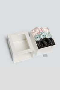 3 Pack Large Silk Scrunchie Set boxed in pink, blue, and black, a refined accessory designed to care for hair with grace.