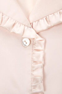 The front placket of Daisy Women's Pink Pajama Top is detailed with round, engraved buttons that bear the MANITO logo.