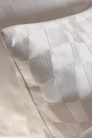 Close-up of Damier Silk Pillow with embossed chessboard pattern and subtle logo.