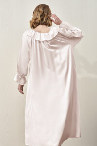 Back view of the female model wearing the pink MANITO Echoes Silk Ruffle Dress, featuring a flowing silhouette.