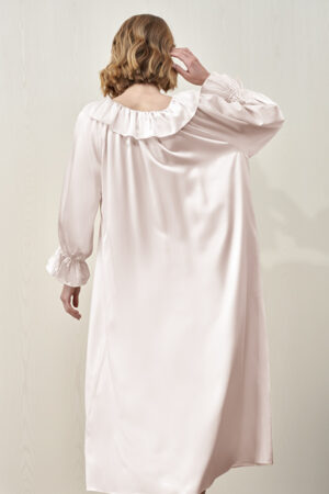 Back view of the female model wearing the pink MANITO Echoes Silk Ruffle Dress, featuring a flowing silhouette.