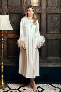 Elegant woman in Fiesta Long Sleeve Silk Nightdress standing in a vintage wood-paneled room.