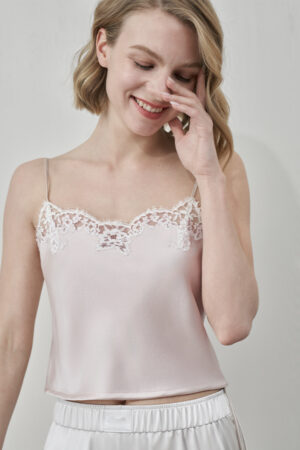 Model smiling in MANITO Flora Lace Silk Camisole Top, showcasing delicate lace neckline on blush pink silk lace top.