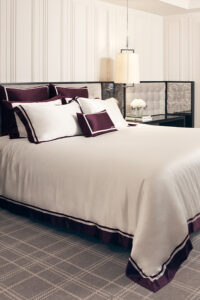 Luxurious MANITO French Trim Silk Bed Duvet Cover in pure white with Bordeaux red trim, elegantly draped over a modern bed.