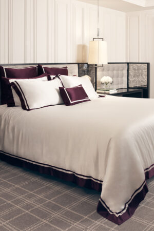 Luxurious MANITO French Trim Silk Bed Duvet Cover in pure white with Bordeaux red trim, elegantly draped over a modern bed.