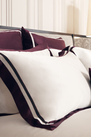 Elegant white silk pillowcases with Bordeaux red trim from MANITO, adding a sophisticated contrast to the bedding set.