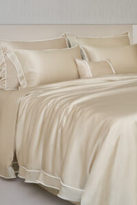 MANITO champagne Fringe Silk Duvet Cover on a bed with matching pillows, showcasing white fringe trims.