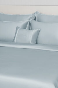 Close-up of MANITO Fringe Silk Duvet Cover with white fringe trims, highlighting the silky texture and elegant pillow arrangement.