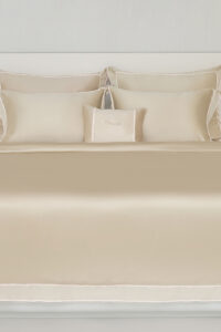 Side angle of a champagne MANITO Fringe Silk Duvet Cover on a bed, featuring luxurious bedroom ambiance.