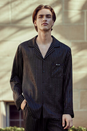 Male model wearing MANITO Galaxy Men's Silk Pajama Set with black pinstripes outdoors.