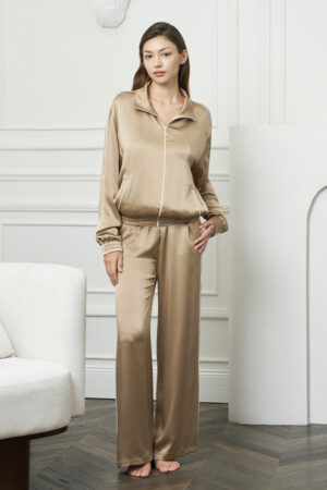 Woman wears Gloaming Women's Pajama Set in twilight gold-brown silk, standing relaxed to showcase the full-length loungewear.