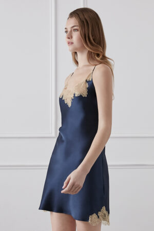 Woman in navy blue lace-trimmed silk dress showing off the delicate design of the dress.