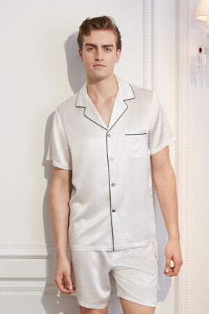 The man is elegant and comfortable in an authentic white short silk pajama set with contrasting trim.