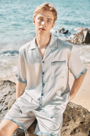 MANITO Inkmark Men's Short Pajama Set with gradient blue trim, shown worn at the beach.