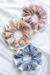 Two-tone Silk Scrunchies in pink, champagne, and blue, showing soft silk and peony-white ruffle that gently fit on hair.