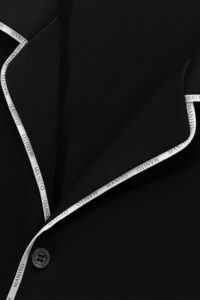 Close-up of the MANITO Jersey Men's Modal Silk Pajama top, highlighting the iconic logo ribbon and a button.