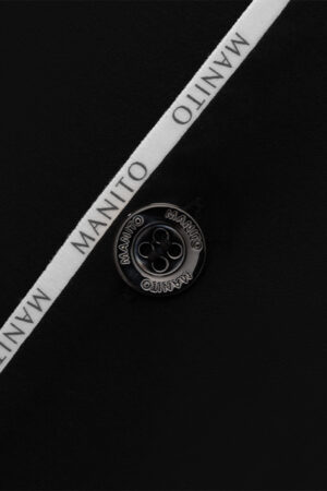 Extreme close-up shot of the MANITO logo button and iconic ribbon on the Jersey Modal Silk Pajama.