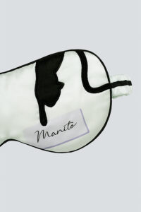Detail shot of MANITO cat eye mask in mint green with cat head embroidery and signature branding.