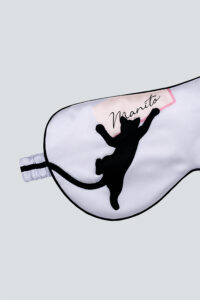 White MANITO cat eye mask featuring leaping black cat embroidery and pink-accented logo patch.