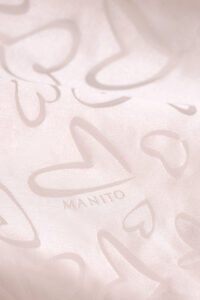 Close-up of MANITO logo and heart jacquard fabric on the Loving Kid's Nightdress.