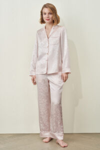 Model wearing the MANITO Loving Women's Pajama Set in pink silk jacquard, featuring heart patterns and a relaxed, elegant fit.