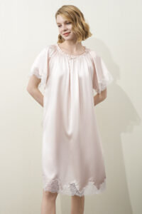 A model wearing MANITO Luella Lace Silk Short Sleeve Dress in pink, featuring a relaxed fit, lace-trimmed sleeves and hem.