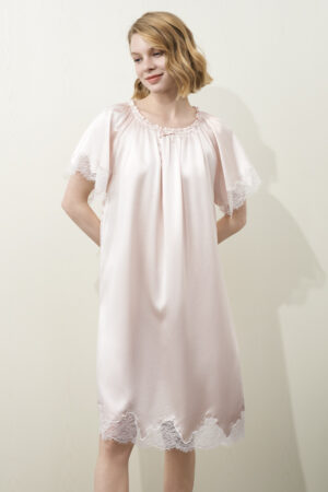 A model wearing MANITO Luella Lace Silk Short Sleeve Dress in pink, featuring a relaxed fit, lace-trimmed sleeves and hem.