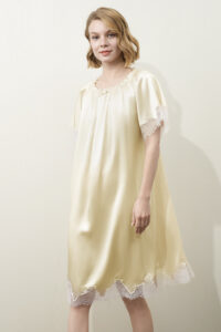 A female model dressed in MANITO Luella Lace Silk Short Sleeve Dress in yellow, showing the airy silhouette.